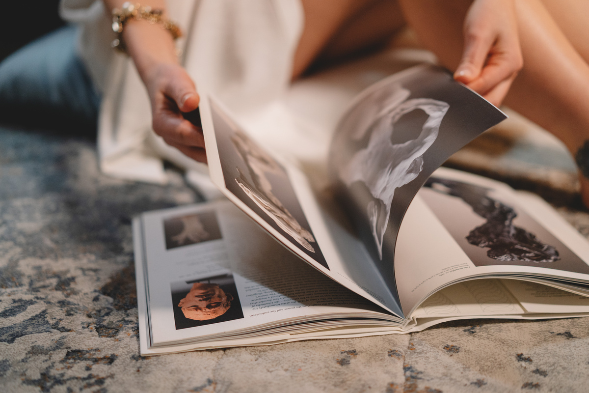 Anonymous woman turning page of magazine sitting on couch