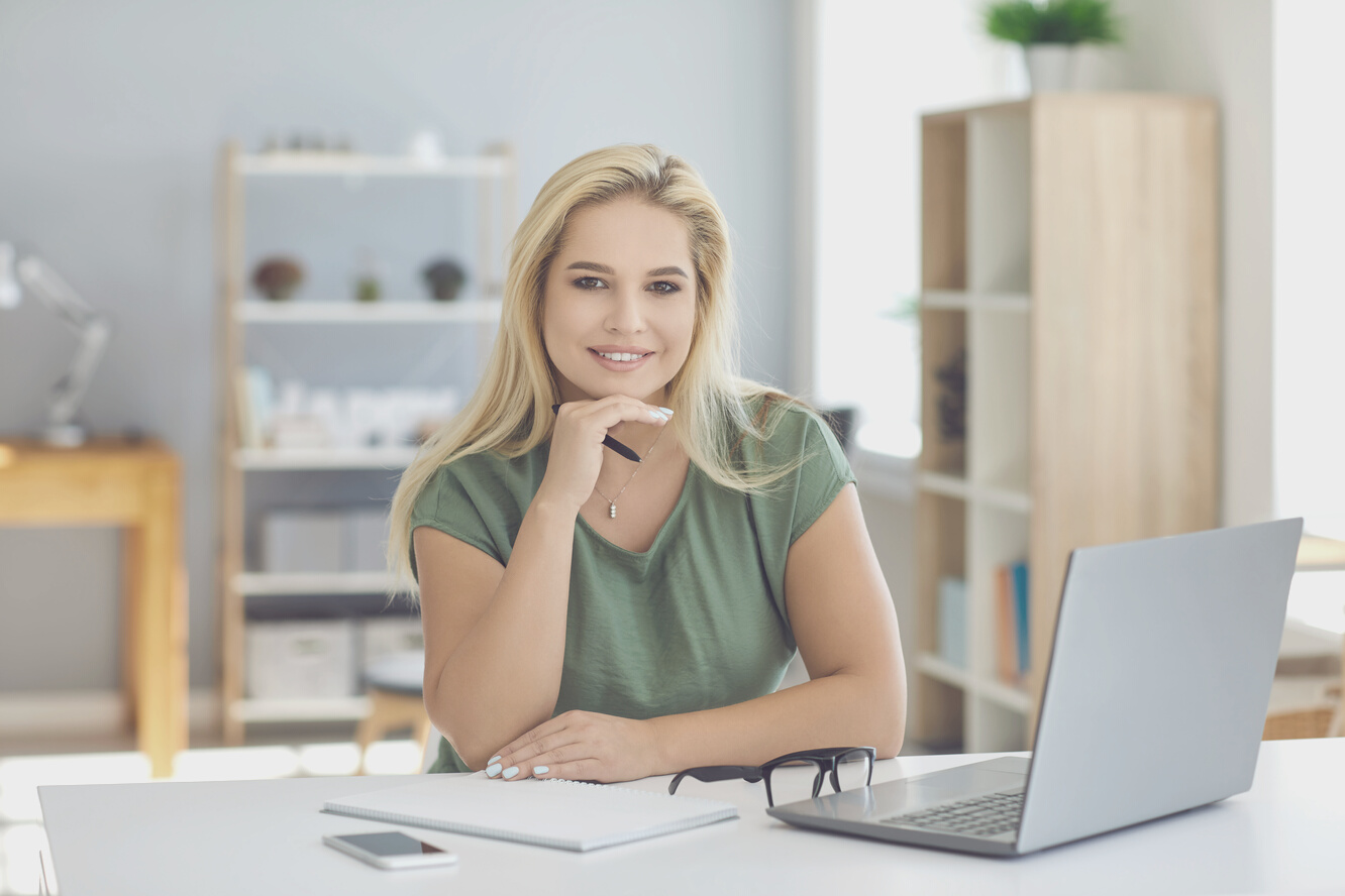 Happy Confident Smiling Business Woman Sitting at Desk with Laptop in Her Office